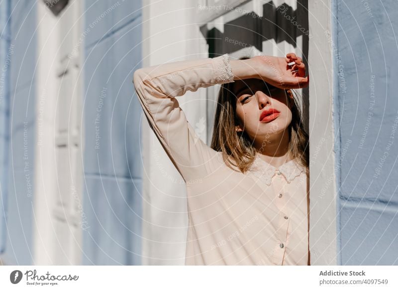 Sensual female protecting face from sun near doorway woman stylish street building sunny protection closed eyes young sensual urban fashion model cool trendy