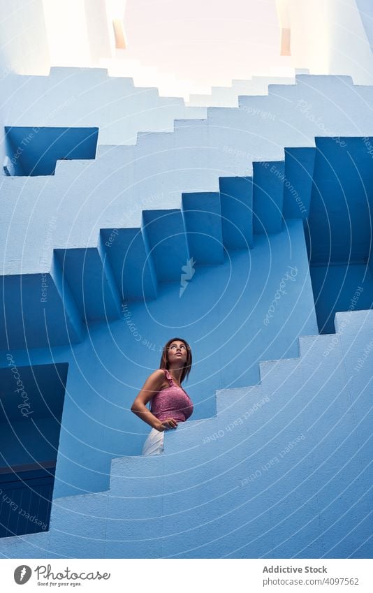 Woman walking upstairs on modern blue building woman long hair elegant construction structure geometric architecture urban facade downtown center wall abstract