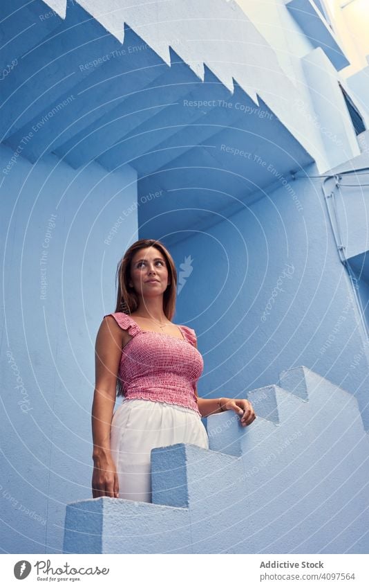 Woman walking upstairs on modern blue building woman long hair elegant construction structure geometric architecture urban facade downtown center wall abstract