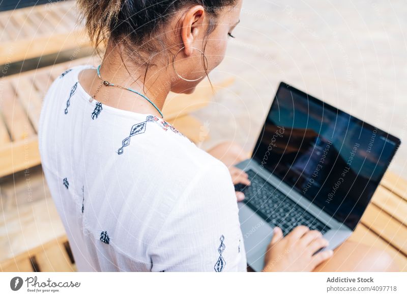 Relaxed woman using laptop while resting on deck chair relaxed browsing cheerful smile wooden terrace tropical sit casual crossed legs costa rica young adult