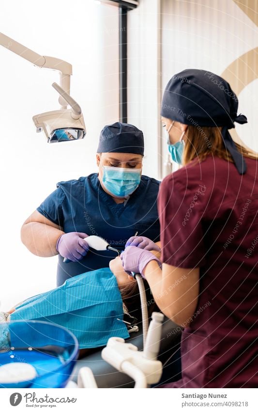 Dental Clinic Workers With Young Patient side view standing two women looking patient examining kid girl young dentist clinic dental clinic lying health care