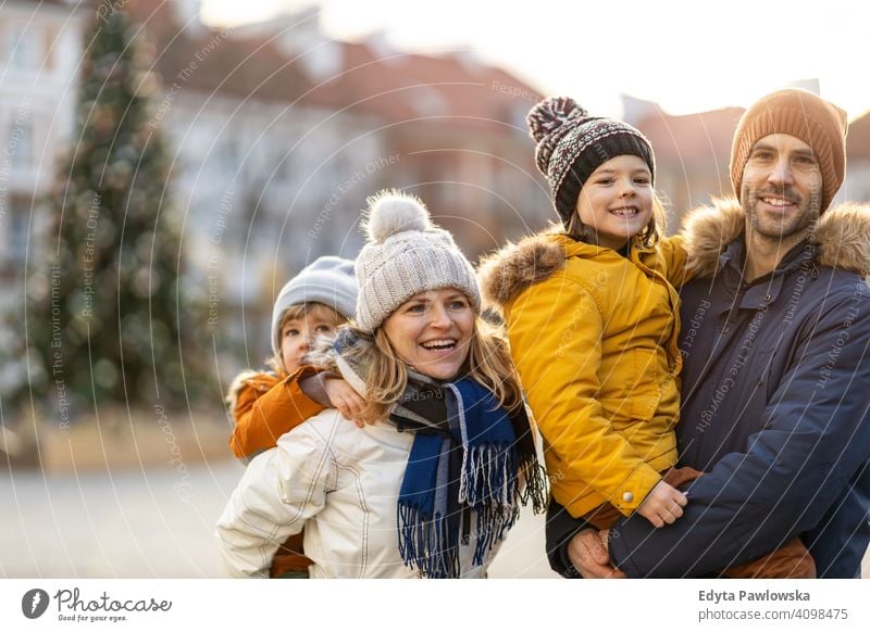 Happy young family having fun outdoors during Christmas winter man autumn father woman mother parents relatives son boys kids children relationship together