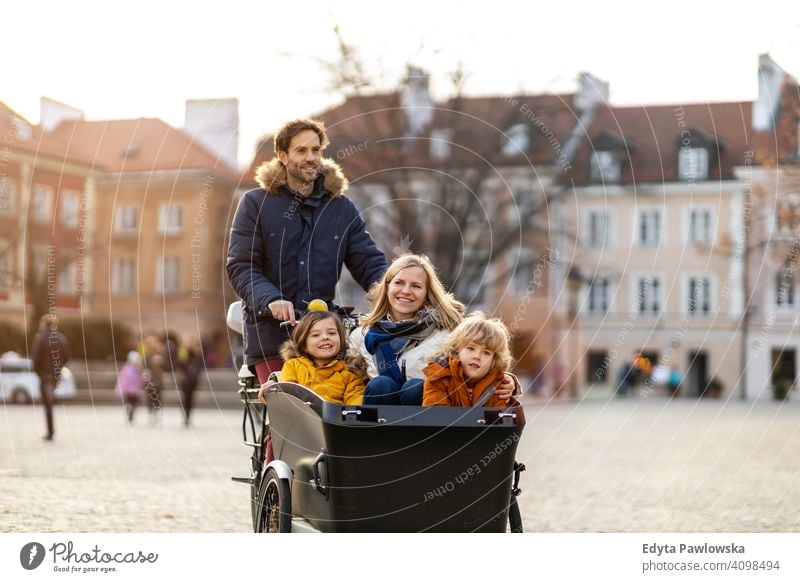 Young family riding in a cargo bike together cycling transport tricycle healthy active bicycle biking modern sustainable transport ecological travel young