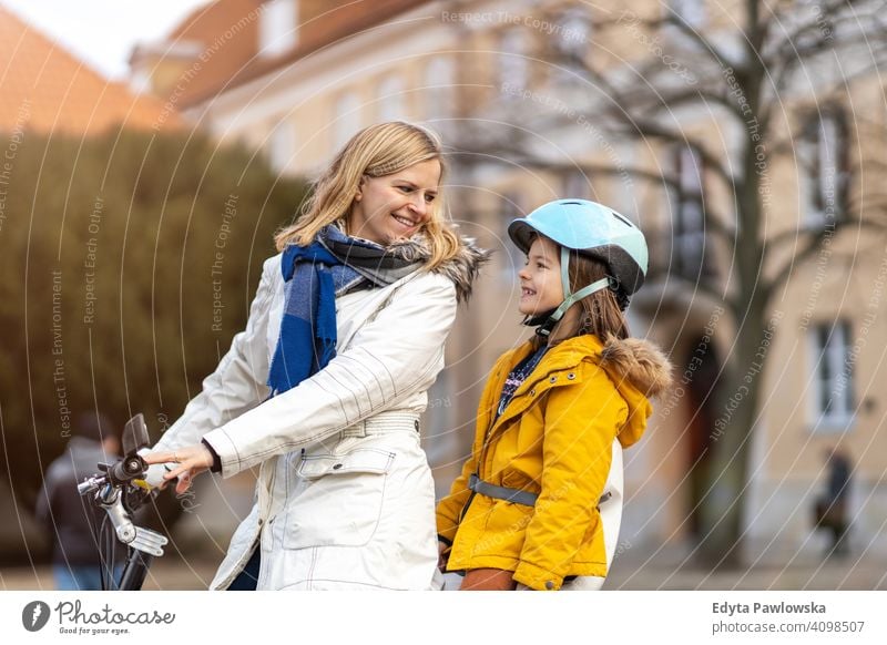 Young woman and her son riding the bicycle in a city young wearing bike helmet cycling winter autumn mother family parents relatives boy kid children