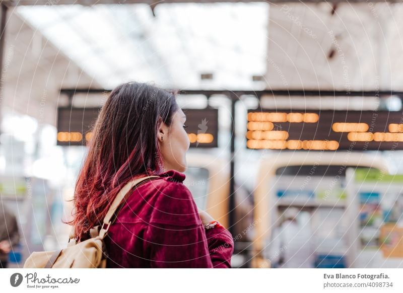 back view of backpacker woman in train station waiting to travel. Travel and lifestyle concept city public transport boards caucasian young trip screen