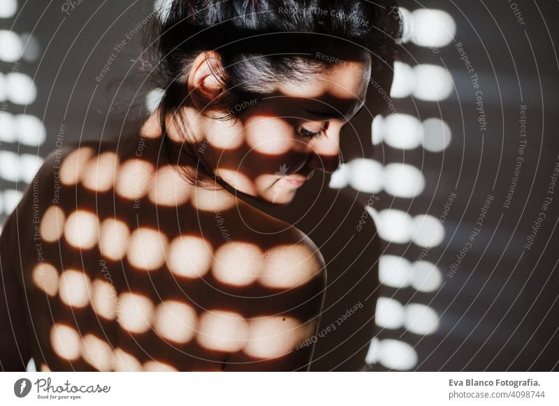 caucasian woman in bedroom with blind shadows. Morning at home morning indoors casual girl skin window contemplation hair wooden harmony hand adult sunlight