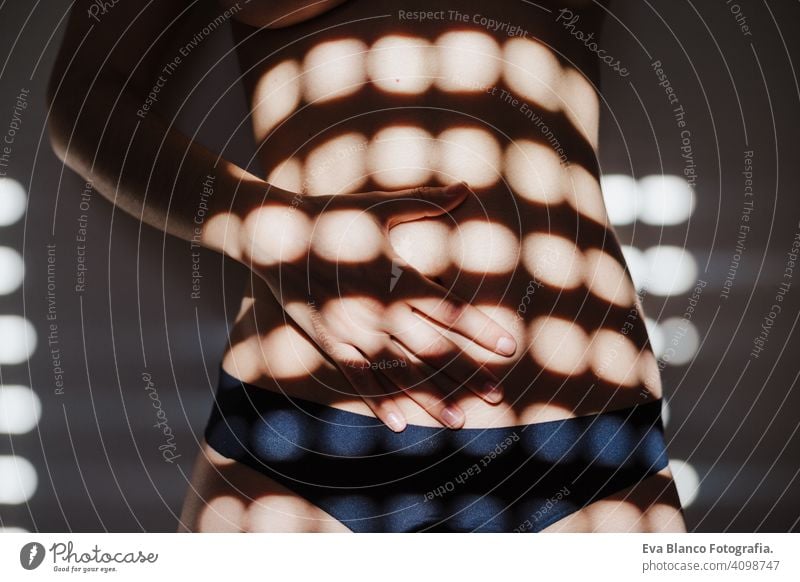 caucasian woman in bedroom with blind shadows. Morning at home morning indoors casual girl skin window contemplation hair wooden harmony hand adult sunlight