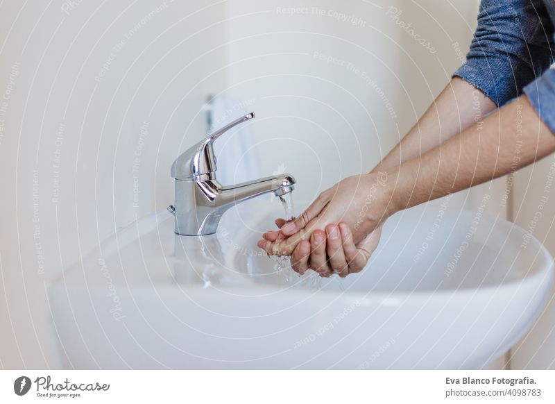 Closeup of caucasian woman washing hands in bathroom to prevent Covid-19 viral infection. Recommended washing with soap and running water during coronavirus pandemic