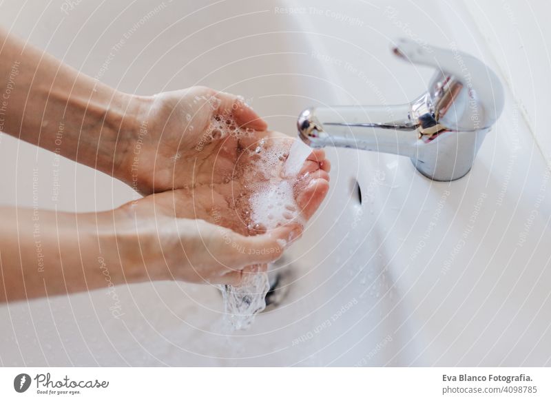 Closeup of caucasian woman washing hands in bathroom to prevent Covid-19 viral infection. Recommended washing with soap and running water during coronavirus pandemic