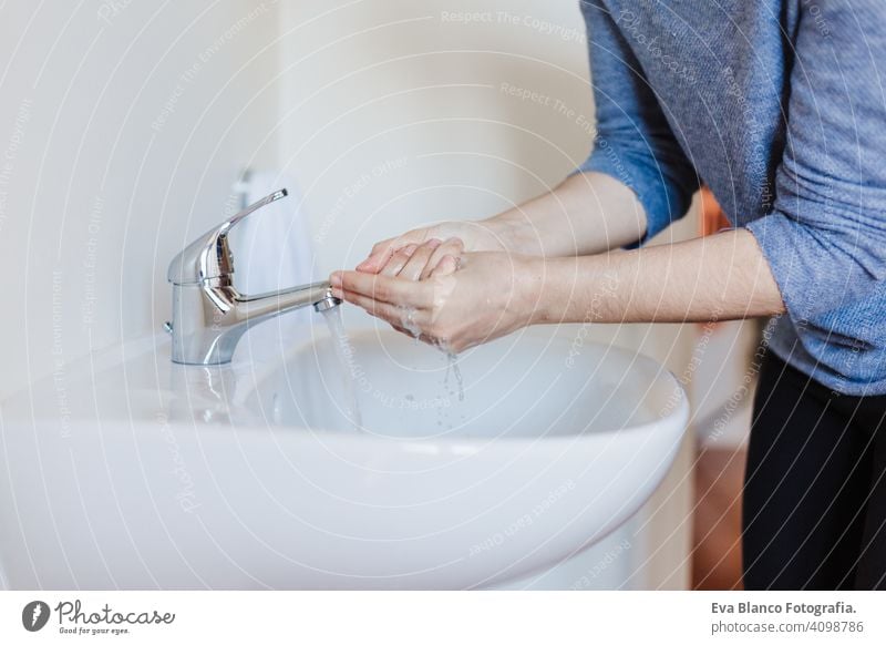 Closeup of caucasian woman washing hands in bathroom to prevent Covid-19 viral infection. Recommended washing with soap and running water during coronavirus pandemic