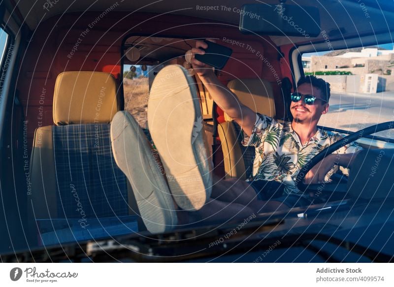 Happy adult man taking selfie with smartphone while sitting in van travel road trip cheerful moment social media relax use male rest chill lounge message share