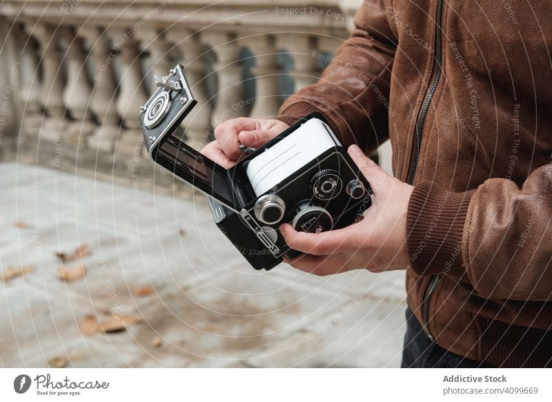 Crop traveler changing film in camera tourist photo camera change street london retro man autumn vintage casual equipment photography hobby city town