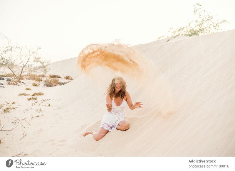 Woman having fun throwing sand in desert woman dune summer tropical vacation adult beautiful relax travel holiday playful recreation activity freedom active