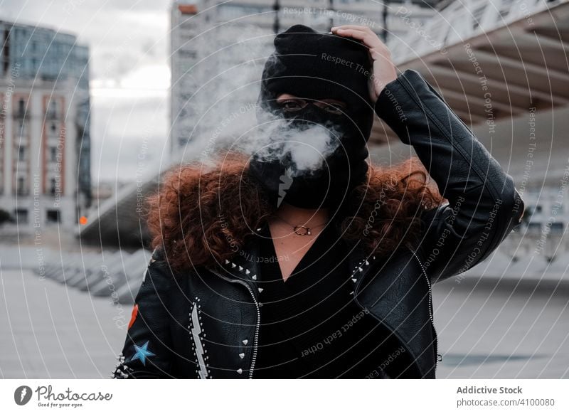 Woman in black mask and jacket smoking on street woman balaclava leather rock urban style stripes brunette fashion city outfit young female underground clothes