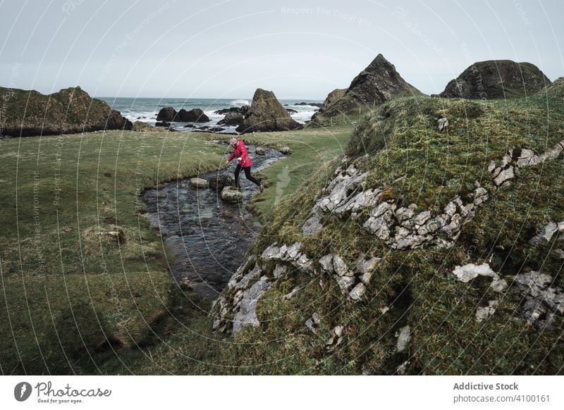 Woman walking along mountain river estuary woman rock landscape stream cliff sea shore flow coast water shallow creek highland scenic seascape female ballintoy