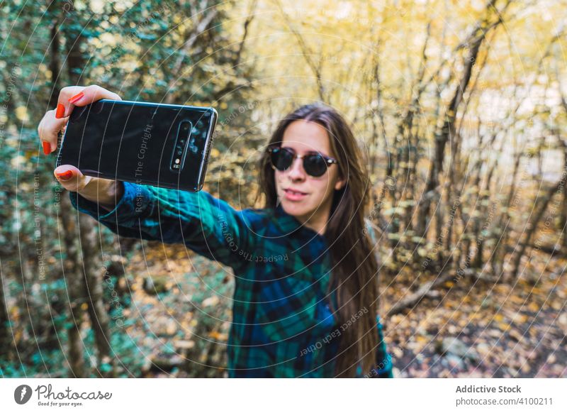 Casual tourist making photo on smartphone of nature woman taking autumn tree selfie woods using browsing device gadget forest picture camera leaf vacation