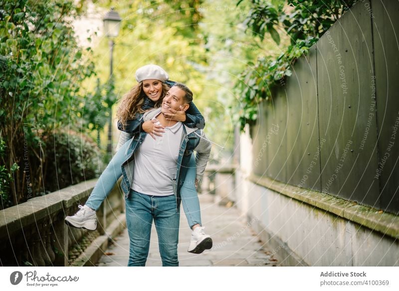 Happy couple having fun together at overgrown city street walking kissing spending tine happy woman sitting back leisure summer young nature lifestyle smile