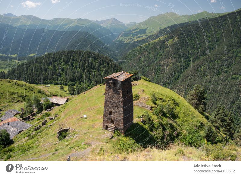 Tall old defensive building in majestic mountains in summer sunny day tower valley stone village ancient historical tourism highland fortress heritage travel