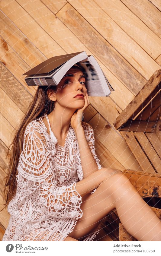 Young woman with a book on her head young student education bored female school university reading study sitting tired girl wood brown knowledge indoors