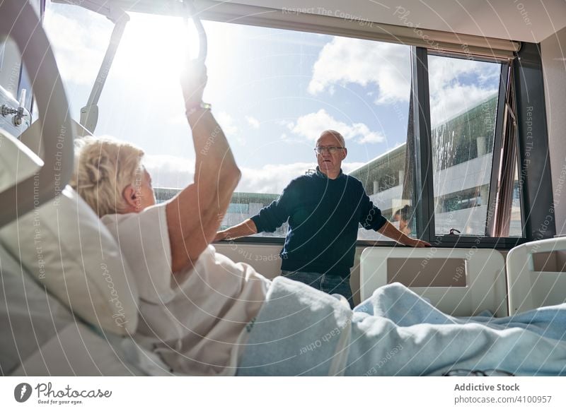 Elderly couple talking in hospital ward visitor patient elderly window man woman medicine healthcare speak conversation communication wife husband senior mature