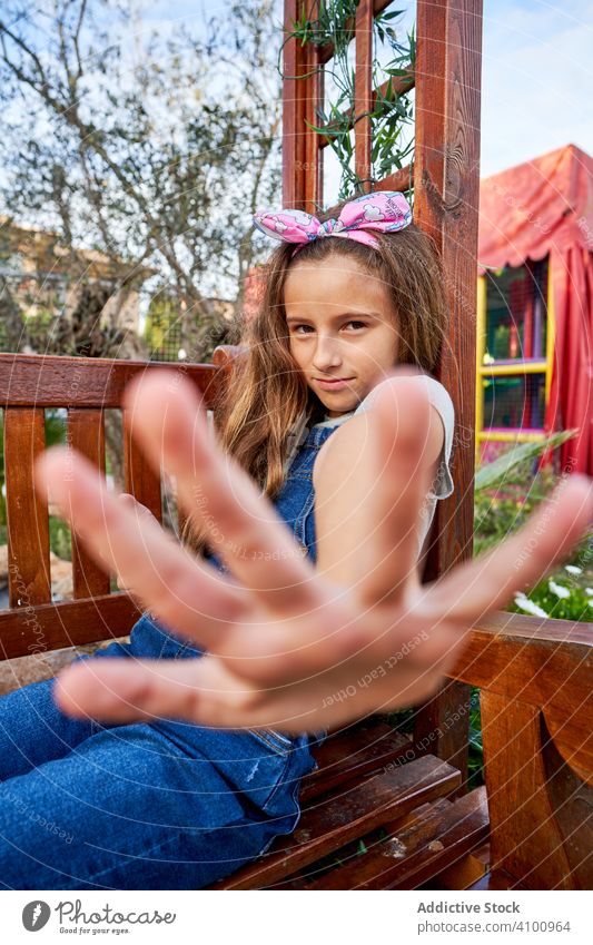 Cute girl playing on smartphone on playground stop positive chat social media gesture no hide reject using kid browsing fun playful secret prohibited