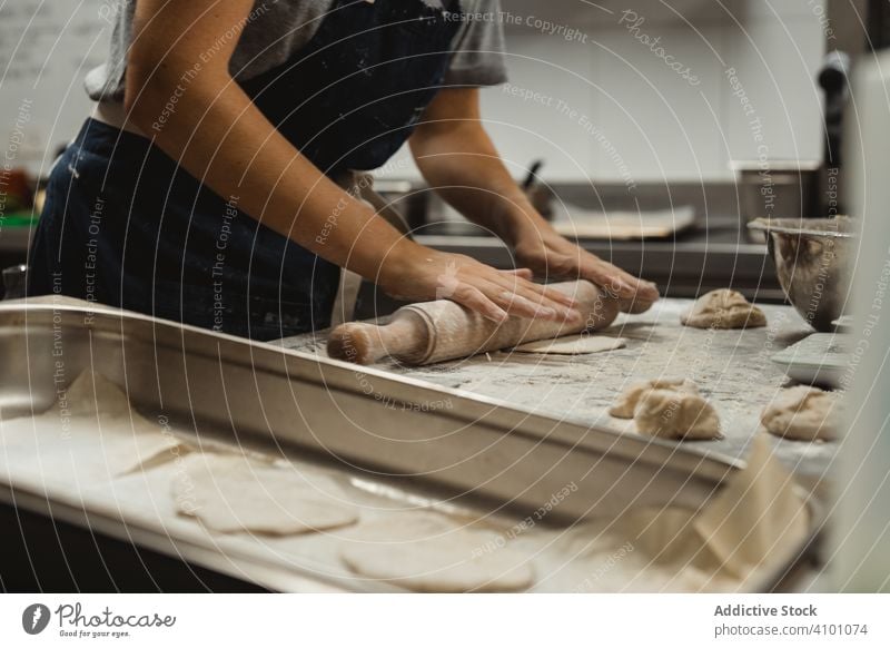 Baker rolling out dough in kitchen bakery bread food pastry flour meal rolling pin table wheat chef restaurant preparation flat making recipe ingredient