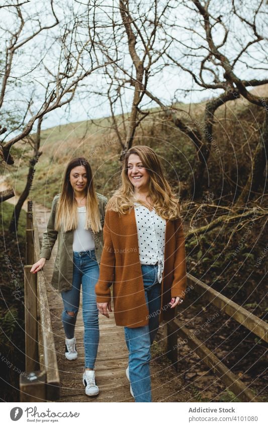 Women walking on wooden footbridge in spring day women countryside explore cheerful together happy sister tree nature pedestrian tourism trip journey activity