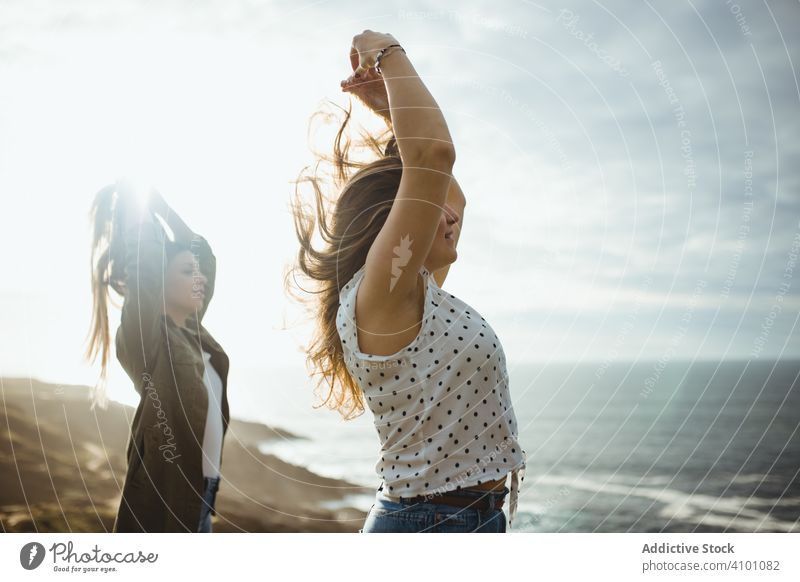 Happy female travelers enjoying freedom at seaside women breeze fresh flying hair sister stand harmony countryside together happy relax smile nature wind ocean