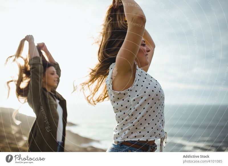 Happy female travelers enjoying freedom at seaside women breeze fresh flying hair sister stand harmony countryside together happy relax smile nature wind ocean