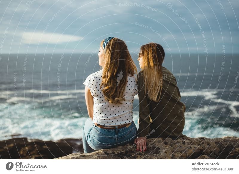 Dreaming women sitting together on shore and enjoying sunrise dream seashore rock sister harmony bonding contemplate relax ocean close seaside stone nature