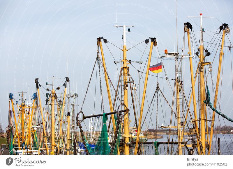 Crab cutter on the North German Wadden Sea. Boat masts with Germany flag Harbour fishing Mud flats German flag Fishing boat Fishery North Sea Competition Net