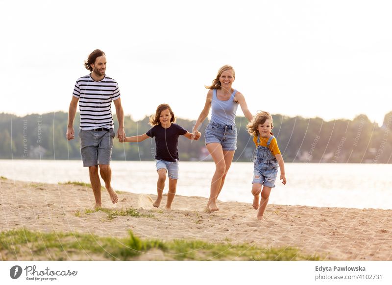 Young family having fun outdoors at the beach sea lake holidays vacation nature summer parents son boy kids children together togetherness love people happy