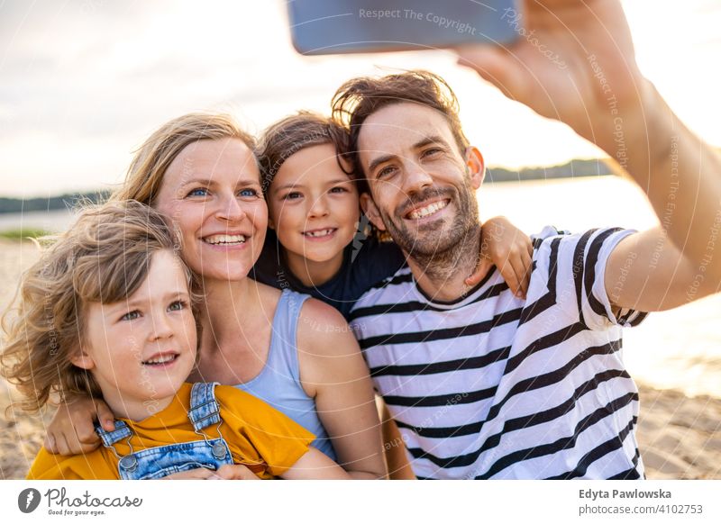 Young family having fun outdoors at the beach sea lake holidays vacation nature summer parents son boy kids children together togetherness love people happy