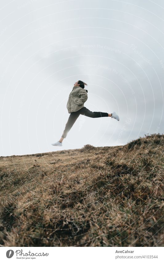 A young woman jumping over the grass while the sun reflects everywhere liberty and relax concept with copy space person female ocean loneliness senior solitude