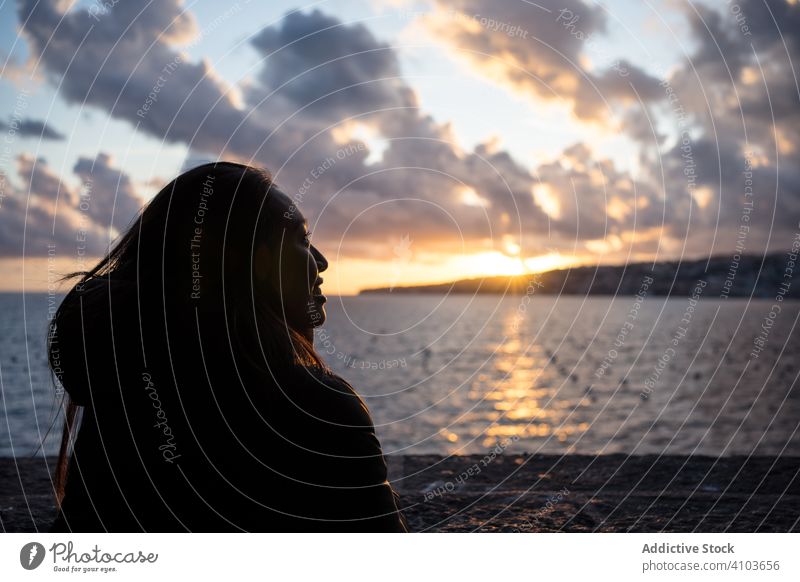 Joyful female on vacation in warm wear delighting in sunset on seashore woman cloud sky smile enjoy laugh travel tourism relax water beautiful beach holiday