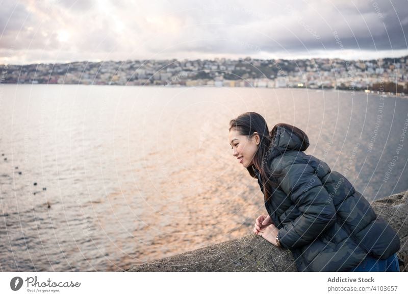 Woman on vacation in warm wear delighting in sunset on seashore woman cloud sky smile female enjoy laugh travel tourism relax water beautiful beach holiday