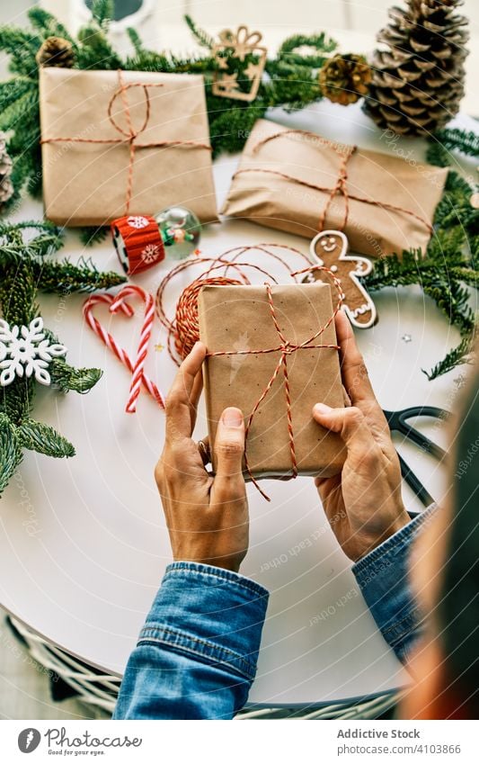 Person preparing christmas gifts with rope and christmas decorations present holiday box xmas paper ribbon red wrap celebration decorative winter handmade bow