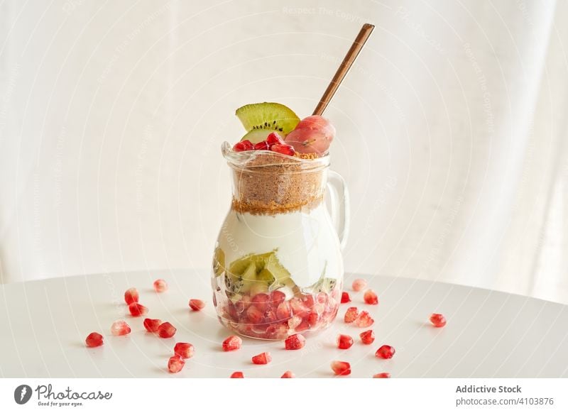 Delicious yogurt dessert with pomegranate, kiwi, grape and ginger biscuit white natural organic diet fruit sweet healthy food breakfast fresh red snack closeup