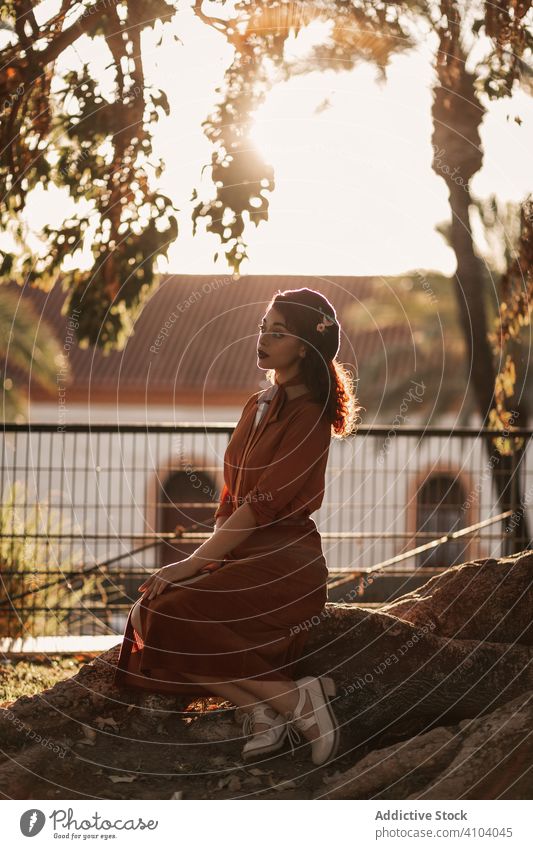 Pensive woman in crossed pose wearing vintage clothes sitting on stone in park pensive romantic crossed legs dreaming young eye thoughtful beret contemplative