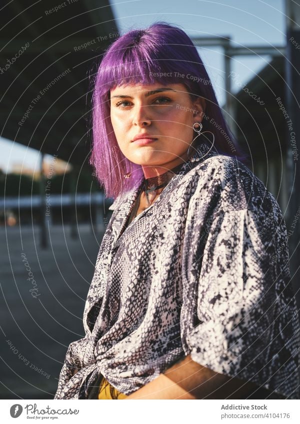 Woman with purple hair in yellow pants sitting on metal fence woman stylish hairstyle shiny wall fashion young urban model street human female outfit hipster