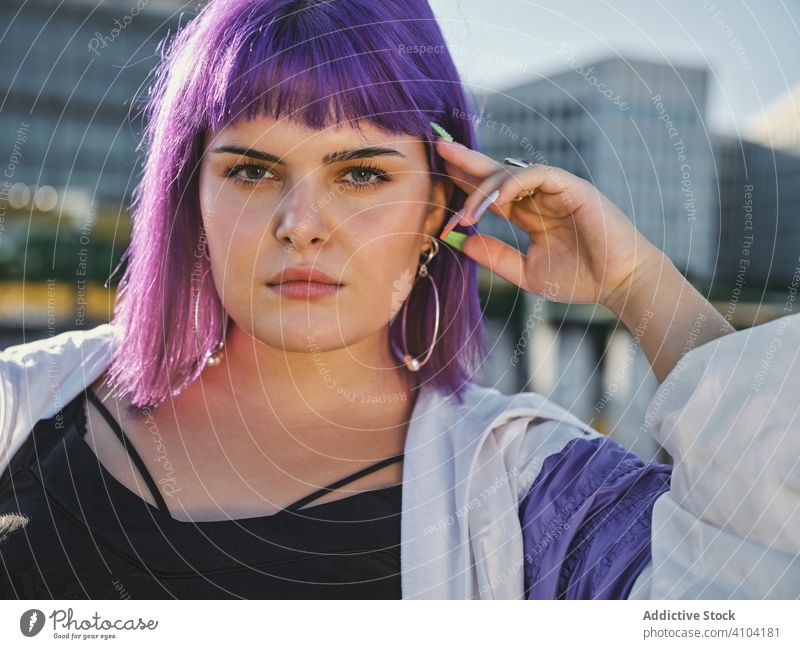 Woman with purple hair leaning on metal fence woman touching stylish urban hairstyle jacket shiny district confident fashion young model street human female