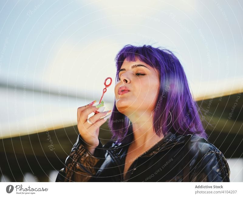 Woman blowing bubbles in bright day woman purple stylish funny cute soap cheerful laughing lovely hairstyle playing joy having fun healthy creativity playful