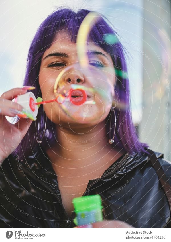 Woman blowing bubbles in bright day woman purple stylish funny cute soap cheerful laughing lovely hairstyle playing joy having fun healthy creativity playful