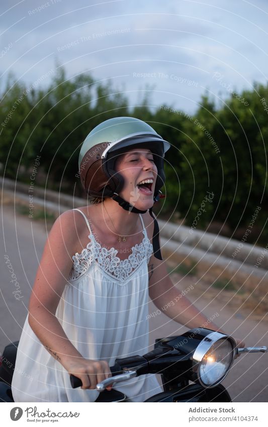 Happy woman riding motorbike motorcycle travel vacation female freedom green plant tree sky helmet heaven street road smile lifestyle laugh enjoy transport