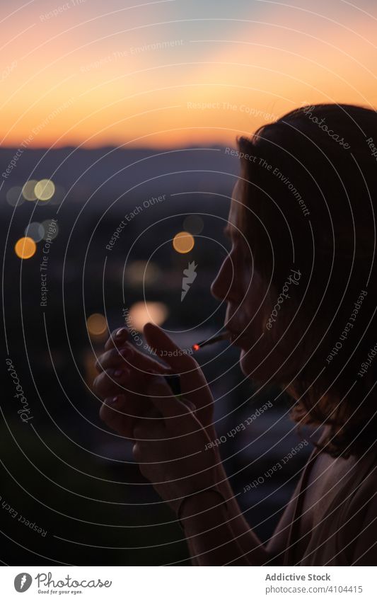 Woman using lighter with cigarette at dusk woman relax smoking resting sunset evening nature sky heaven female lady lifestyle unhealthy carefree peaceful serene