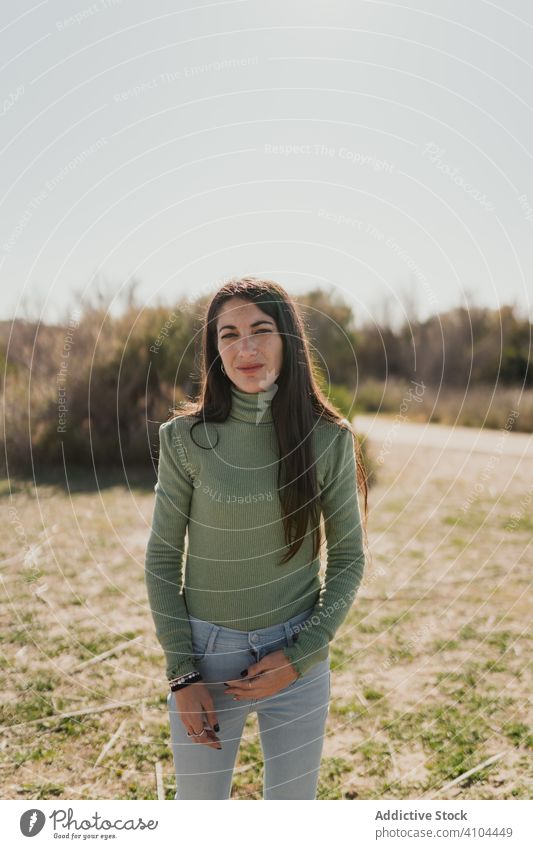 Pensive ethnic woman standing in countryside pensive thoughtful lifestyle think solution serious female casual imagination decision dilemma nature grass day