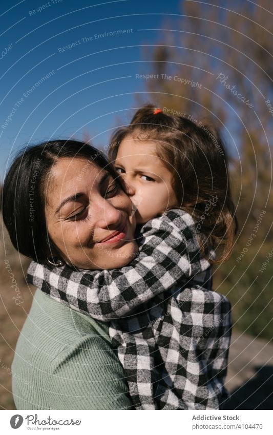 Mother kissing and hugging daughter mother child girl cuddle kid affection together weekend rest childhood activity countryside ethnic day adorable lovely