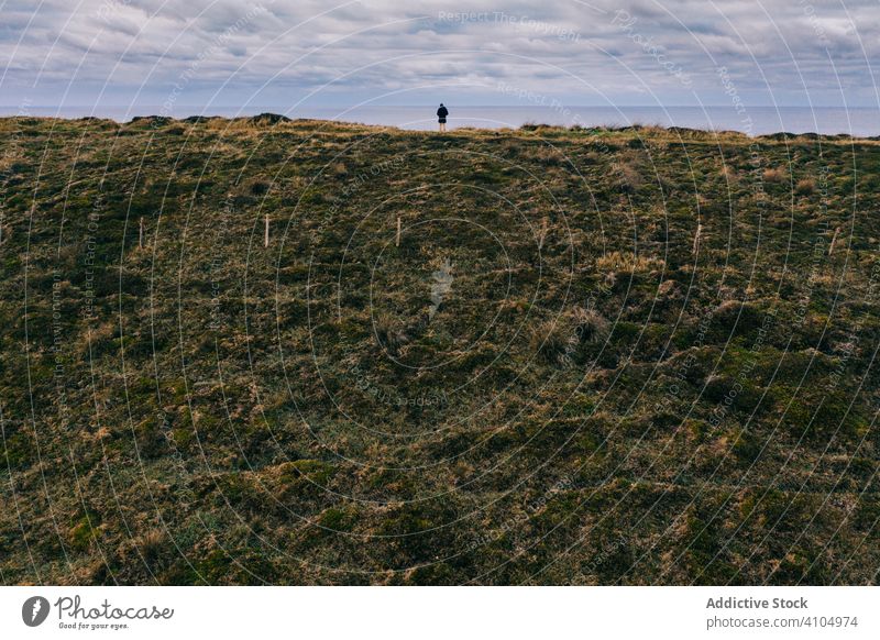 Lonely person standing at  edge of sheer hilly green clay and looking at horizon landscape valley pielagos cantabria santander spain cloudy sky botanical travel