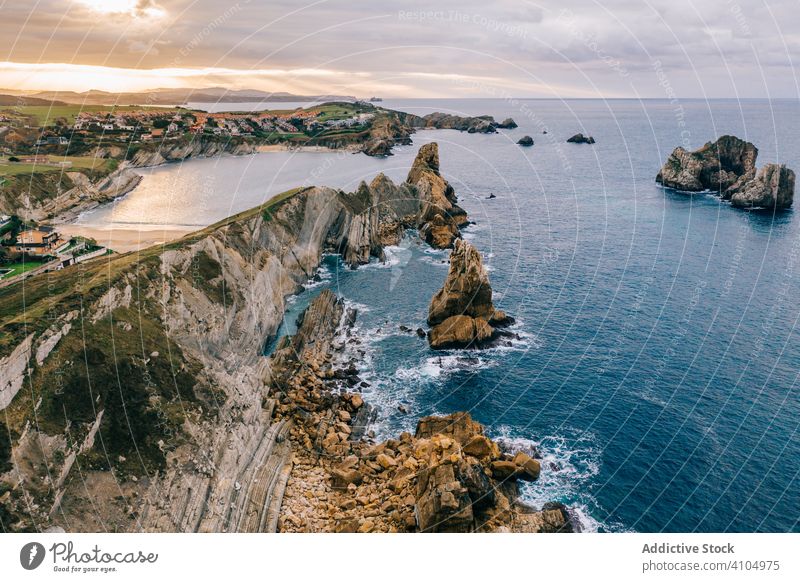 Stone peaks and seashore and foamy waves under cloudy sky scenery ocean water nature landscape travel scenic cantabria santander pielagos spain coast