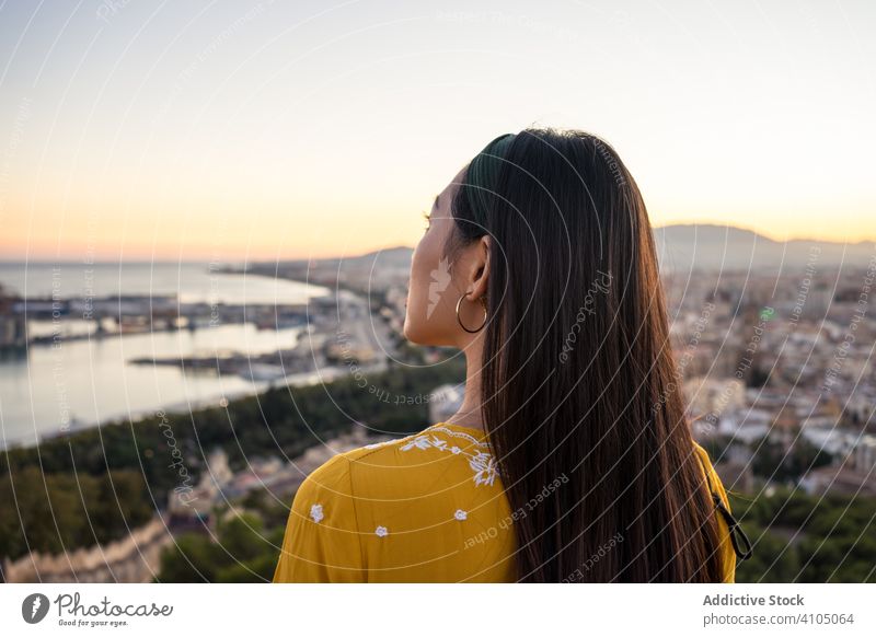 Ethnic tourist against city and sunset sky woman tourism smile sea ethnic castillo gibralfaro malaga spain female ruin travel trip journey coastal cityscape